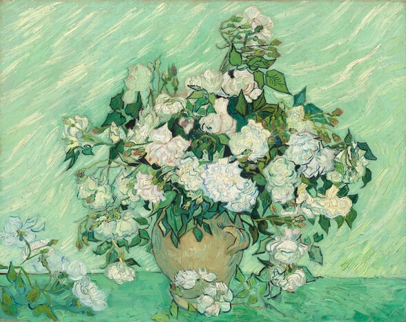 A profusion of white roses bursting from the neck of a tan jug almost fills the height of this horizontal still life painting. The roses have large, round blooms with petals tinged with denim and aquamarine blue, sage green, mauve pink, teal, and butter yellow. Emerald-green leaves fill the spaces between blossoms. The jug has a short, rounded handle and sits on a sea glass-green surface. A few blooms lie in the lower left corner and at the foot of the vessel. Many of the flowers, leaves, and vase are outlined with navy blue or black. A mint-green wall with wavy, diagonal streaks of cream white fills the background. The paint is applied thickly with visible strokes.