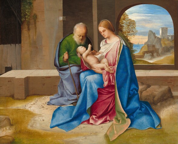 An old man and a young woman holding an infant are seated together in the center of this almost square painting. They are all fair-skinned. To our left, the man sits on a low, tan brick wall with his head bowed to look at the baby on the woman’s lap. A periwinkle-blue cloak is wrapped around the kelly-green robe that covers his shoulders, back, and legs. One hand grips a short staff planted on the ground. His receding white hair and beard are thin and scraggly with tufts sticking out over his ears. The woman sits next to and slightly in front of him, to our right, on a low rock, her body angled toward the man. A long, cobalt-blue cloak is draped around her shoulders and covers her knees over her rose-pink gown. Her honey blond hair is parted in the middle and gathered at the back of her head. Her brown eyes look down at the infant, who also is blond with brown eyes. A long white shawl is tucked into the neckline of her dress, drapes over her shoulders, and wraps under the baby as she cradles his body with one hand under his rump and the other behind his head. The baby lies on his back with his head turned toward the woman, and he points to her with one outstretched arm. The dirt ground is scattered with pebbles that make a loose ring around the trio, with moss-green growth to either side. A camel-brown brick wall fills the upper half of the composition behind the people and extends off the top edge. A rounded arch pierces the back wall to our right of the woman. On the other side of the opening, chestnut-brown trees grow up along the left and the landscape beyond opens onto rocky hills with a white, square tower. In the deep distance, the silhouette of a town is painted in robin’s egg-blue against a pale peach horizon line. Thin, white clouds skim across the watery blue sky above.