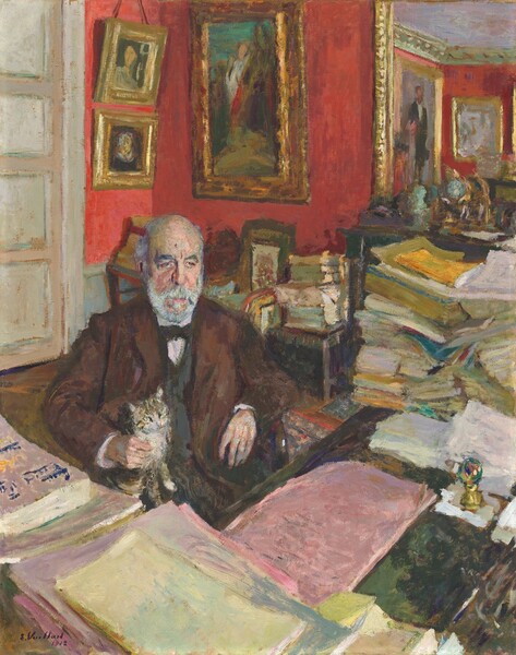 We look slightly down onto a balding, bearded man with pale, peachy skin and wearing a three-piece suit, seated in a wooden armchair behind an L-shaped desk, in this loosely painted vertical portrait. A tabby cat with a white chest sits on his lap. The room around them is packed with piles of papers, books, and paintings hung on scarlet-red walls. The man’s body faces us, and he looks off to our right under dark, bushy, peaked eyebrows. His round head is fringed with gray hair, and he has a full, light gray beard. His gray eyes are bloodshot beneath heavy lids, with dark rings underneath. He has a short nose, and the flesh of his cheeks hangs in loose paunches alongside his nose. Close inspection finds strokes of plum and lavender purple, mint and sage green, and ice blue creating highlights and shadows on this face. His left hand, to our right, hangs loosely over the arm of the chair, while his other hand gently rests around the chest of the small cat that sits on his lap. The man wears a chocolate-brown jacket over a charcoal-gray vest, and a dark bowtie with a white shirt that just shows at his throat and wrists. Reams of pink, yellow, white, green, and gold paper are arrayed on the desk in front of the man, and in tall, uneven piles to his left, with more on a chair against the wall behind him. A small paperweight globe of multicolored glass on a brass base rests on one sheet of paper on the desk. Two small and one large gilt-framed portraits hang on the velvety red wall in the background, and others are reflected in a gilt-framed mirror at the upper right corner of the painting. A white door with four horizontal panels is closed behind the man at the upper left corner. The brushwork in the painting is quick and loose, with touches of contrasting colors throughout. The artist signed and dated the lower left corner, “E. Vuillard 1912.”