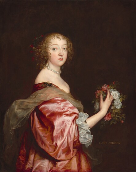 A woman with a smooth, ivory complexion stands wearing a voluminous rose-pink, silk dress and holding a wreath of pink and white roses and greenery in this vertical portrait painting. Shown from the hips up, her body faces our right in profile but she turns to look at us from the corners of her dark gray eyes. Her light brown hair is pulled up but curls frame her oval face and pointed chin, and falls in ringlets to the base of her neck. She has gently curved eyebrows, a straight nose, and her small pink lips are closed. She seems to wear some red flowers in her hair, but these are lost in the dark brown, nearly black, background. She wears a short necklace made of large round pearls and large, teardrop pearl earrings hang from her lobes. Her long pink dress is cut low across her bust and wraps around her shoulders and across her back. A pearl adornment is affixed to her dress at the shoulder we can see. The sleeve of her right arm, closer to us, billows to her forearm, which ends with a wide white ruffle cuff. She holds the rose wreath with her right hand up at chest height. A sash of stiff, crinkled, tan, sheer fabric loosely wraps around her chest and back. The inscription “LADY AVBIGNY” is painted in light tan block lettering against the dark brown background at the woman’s waist level on our right.