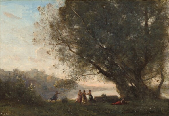 We look across a grassy expanse leading to a lake, with several women, tiny in scale, dancing under a grove of trees to our right in this horizontal landscape painting. Painted with soft, almost feathery brushstrokes of fern and moss green to suggest leaves, two massive trees nearly fill the right half of the composition. Three light-skinned women wearing voluminous togas over one shoulder link hands in a circle beneath the tree, near the lower center of the painting. Lit by the low sun, the woman to our left wears rose pink, the center woman shimmering yellow, and the third woman emerald green. Another women to our left, wearing sapphire blue, runs toward the trio with arms outstretched. A fifth woman wearing a scarlet-red skirt reclines near the tree trunks to our right. A low, rectangular box about the length of a dining room table sits on the grass between the trio and the reclining woman. A few brushstrokes suggest flowers or plants on the box. The lake beyond is painted with smooth strokes of pale apricot and shell pink. A bank of bushes or tall vegetation close to us to our left is painted with touches of forest and olive green, with pale yellow to capture light glinting off the uppermost leaves. Beyond it, and hazy in the distance to our left, a large white building is nestled high on a hill painted in tones of muted plum purple and flaxen gold. Pale, fawn-brown hills lead down to the water in the distance, farther back along the lake. A few thin clouds float in the ice-blue sky above. The scene is loosely painted with visible brushstrokes and touches, so some details are difficult to make out. The artist signed the work in the lower left corner: “COROT.”