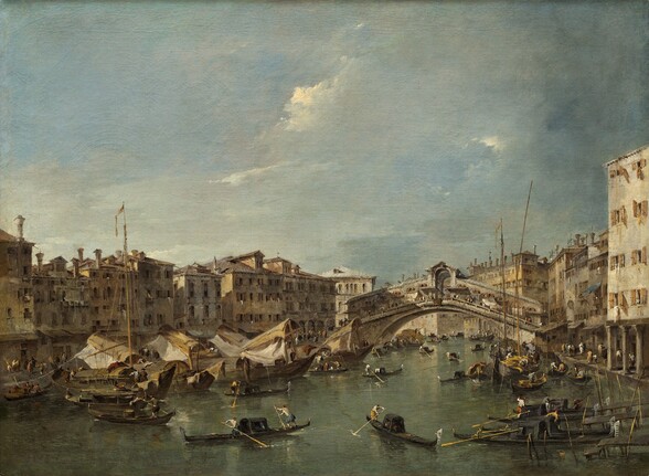 We look down and across a canal filled with more than two dozen gondolas and sailing boats, and flanked by rows golden-yellow and parchment-white buildings connected by a wide, arched bridge in this horizontal landscape painting. Some of the boats are pulled up to the buildings lining the water, and others weave through the canal, guided by one or two people each. Closest to us, two long, low, slender gondolas are angled toward each other. Other boats have curving, cabin-like structures, and there are three sailing ships with tall masts among the gondolas. The densely spaced buildings along either side of the canal have three or four stories with rows of dark, rectangular windows, but some have five stories, like the building closest to us to our right. Laundry hangs from some windows or from balconies, and rooflines are lined with low chimneys. The two banks of the canal are connected by a fawn-brown, stone bridge with a wide, arched span. The deck is covered with an arched walkway filled with pedestrians. The canal extends into the distance and turns a corner, so the rows of buildings create a screen beyond the bridge. Tiny in scale, people walk along both sides of the canal. Touches of white, black, brown, and harvest gold suggest clothing and hats. The water and buildings take up the lower third of the composition. Against a pale blue sky, a screen of white clouds darkens to flint gray in the upper right corner.
