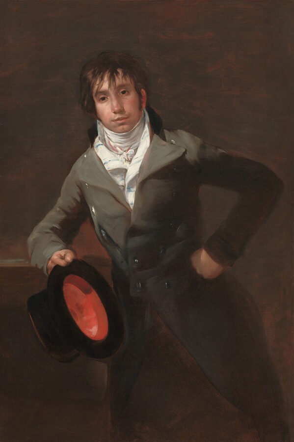 Shown from the knees up, a cleanshaven, young man with pale, peachy skin leans on his right elbow, to our left, against a ledge and holds a black top hat in that hand in this vertical portrait painting. His body faces us and he looks slightly off to our left, as if just over our left shoulder, with dark eyes. He has a wide nose, his pale pink lips are closed, and he has the hint of a five o’clock shadow on his square jaw and cleft chin. Sideburns come down past his ears, and straight brown hair falls in long bangs over his forehead and around his eyes and ears. White cloth wraps around his neck and is tied in a knot at the base of his throat. His white vest is striped faintly with light blue. Over that, his gray jacket has a black collar at the back and wide, gray lapels that reach his shoulders. The jacket is fitted to his waist, where it is buttoned, and then flares out into the shadows at his knees. Silver buttons gleam in the light from our left, down that side of the jacket. His left fist, on our right, rests against his hip as he leans on his other elbow, presumably on a ledge or high table. He holds the black top hat in that hand so we see the crimson-red lining within. The dark background behind him is subtly streaked with brick and coffee brown.