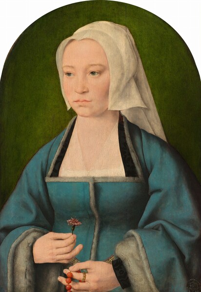 A woman with smooth, pale skin, wearing an ivory-white headdress and a peacock-blue dress, is shown from the hips up in this vertical portrait painting, which has an arched top. The woman’s body and face are angled to our left, and she looks off in that direction with gray eyes. Her smooth cheeks are lightly blushed in her heart-shaped face. She has a high forehead, faint brows, and her full, pale pink lips are closed. Narrow panels of her headdress come down the sides of her face, emphasizing the heart shape. The fabric covers her head and falls in a veil down her back. Her dress comes up high across the back of her neck and then flares out to nearly her armpits across a low, straight neckline. Sheer fabric covers her chest, and the inner part of her neckline has a band of black to each side. The blue dress is lined with gray fur along the neckline, down the front, and on the undersides of voluminous sleeves, which are turned back at her wrists. Black cuffs peek out from under the folds. In her right hand, to our left, she holds a single pink carnation in front of her abdomen with her thumb and first two fingers. She wears a gold ring on the pointer finger of her other hand, in which she holds a string of coral-red beads. A hint of a gold belt is just visible between and behind her hands. The green background behind her glows around her shoulders and deepens to moss green around the arched top of the panel.
