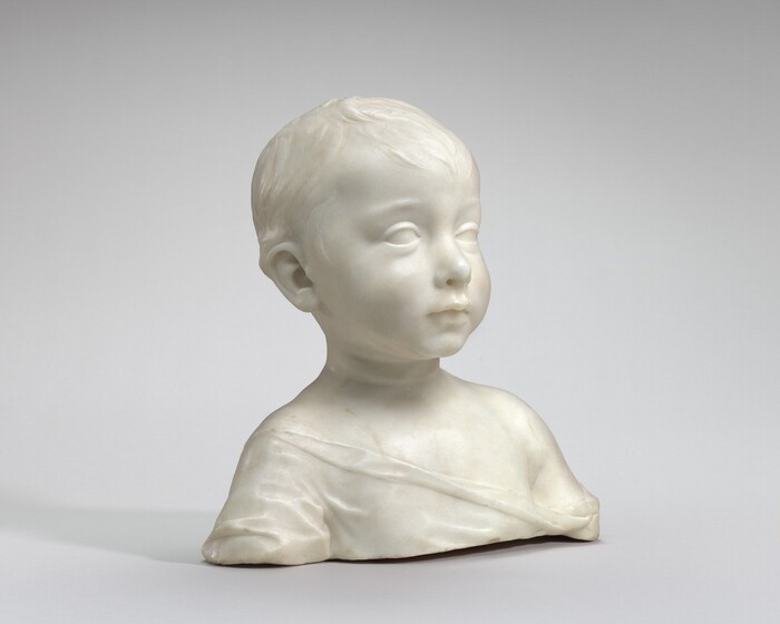 This white marble bust shows the head, shoulders, and upper chest of a young boy. The photograph was taken with the work angled slightly to our right. The boy has full cheeks, a slightly upturned nose, and short, wavy hair. He stares straight ahead, attentive and alert. His loose garment drapes from his right shoulder, on our left, down and across his chest to just below his left shoulder.