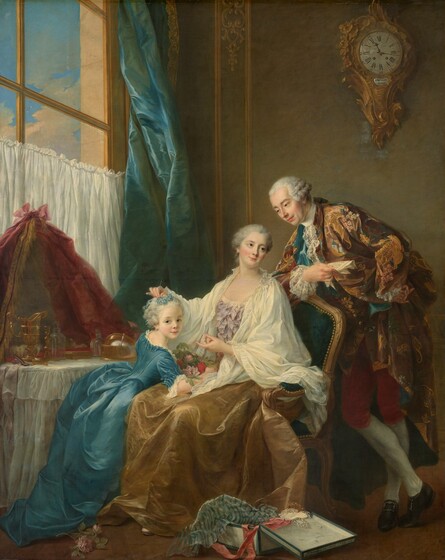 A woman sitting in an upholstered chair near a vanity table touches the hair of the little girl leaning against her lap to our left, as a man leans onto the back of her chair to our right in this vertical portrait painting. The people all have pale skin, flushed cheeks, and their pale gray hair is pulled back and curled. Their pink lips curve in slight smiles, and light glinting off of much of the fabric suggests they wear satin or silk. The woman’s body is angled to our left, toward the girl, but she turns her head back to look up over her other shoulder with gray eyes. A voluminous, cream-white cloth drapes over her shoulders and lap, over a bodice covered in lilac-purple bows and ribbons. Her gold satin skirt falls around her feet. The little girl leans onto one arm on the woman’s lap as she turns to look at us with pale blue eyes. The girl’s forget-me-not-blue dress has a fitted bodice, elbow-length sleeves over white cuffs, a long, full skirt, and white ruffles along the collar. The woman holds blue flowers in the girl’s hair, and the girl’s forearm wraps around a bundle of pink and red flowers in the woman’s lap. The chair is upholstered in teal blue and has a gold frame and a row of gold nail heads along the padded back and arm. The man leans one forearm against the back of the chair as he looks down at the girl. In that hand, he holds a folded piece of paper with writing. He wears a loose jacket decorated with gold pagodas, pink and yellow flowers, and spruce-green leaves against a brown background. Foamy white lace falls back from his cuffs and hangs down from the high white collar of his undershirt. He wears brick-red, knee-length britches, white stockings, and black shoes with silver buckles. His other hand is planted against his hip, and one ankle is crossed in front of the other. A vanity draped with a white cloth sits on the far side of the woman and girl, along the left edge of the painting. It holds gold and glass vessels and boxes, and a rounded mirror at the back is draped with dark pink cloth. The lower half of a window behind the vanity is covered by a white cloth, and the panes continue beyond the top of the canvas. A teal-blue curtain hangs along the right edge of the window, at the corner of the room. A clock with a gold case of swirling, carved designs hangs high on the peanut-brown wall behind the man. On the floor near the chair, blue and white striped tissue paper, a rose-pink ribbon, and a strand of pearls drape over the edges of an open box. Writing along the front edge of the lid of the box reads, “Fs. Drouais. Ce 1 avril. 1756.” A pink rose lies near the girl’s feet, to our left.