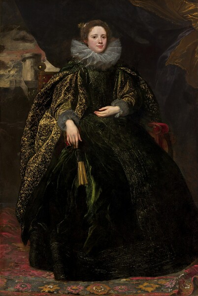 A pale-skinned woman sits on a red velvet chair, which is almost entirely hidden by her voluminous, dark emerald-green and gold gown, in this vertical portrait painting. The woman sits in the center of a shadowed, cavernous space, and her body and dress nearly fill the composition. Her body is turned slightly to our right, and she looks at us from the corners of her large, dark eyes. She has a round face, slightly flushed cheeks, and her full, rose-pink lips are closed. Her tawny-brown hair is pulled back under a headband that glints silver over her right ear, to our left. A goldenrod-yellow flower is tucked into her hair near that spot. Her tall, gossamer lace ruff collar is pleated into figure-eights, and it spans the width of her shoulders. Dots of white paint suggest detailing along the pleated edges. The fabric of her gown is so dark green that it appears black in some places, and it is decorated with bands of gold embroidery down the front of the bodice and full skirt, and around the bottom hem. A cape-like garment splits over long, puffy sleeves, which end with pleated, fog-gray fabric at the wrist. The cape and sleeves are densely ornamented with vegetal designs in glimmering gold. She rests her left elbow, on our right, on the arm of her chair so her hand rests palm up, near her waist. The other hand hangs off the end of the other arm of the chair, which is covered by her sleeve. A closed, black and gold fan hangs on a gold chain near that hand. Her skirt brushes the carpet, which is patterned with floral designs in ruby red, mustard yellow, and charcoal gray. The only parts of the chair that we see are a gold orb finial over her right shoulder, to our left, and the velvet-covered arm of the chair on the opposite side. Above the woman to our right hangs the edge of a muted gold curtain. The woman is lit from behind us, and the space around her is largely swallowed in shadow. Another curtain is lifted in the room behind her. Through it, we look out onto a landscape with a stone tower and buildings under a sky swirled with parchment brown, steel gray, and a sweep of brick red.