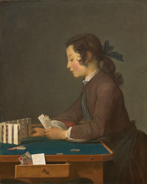 Seen from about the lap up, a young person with brown hair and a peachy complexion, facing our left in profile, leans onto a table and sets folded cards up in a row in this vertical painting. Shown against a dark background, his long hair curls by his ears and is pulled back with a navy-blue ribbon at the nape of his neck. He has a delicately sloping nose, his pink lips are closed, the cheek facing us is flushed, and he looks down at the tabletop under lowered lids. He wears a chestnut brown, long-sleeved coat with a dark blue sash across his chest and tied around his waist. The white of his undershirt peeks out at the high neck and wrists, and the brick-red lining of the sleeve of his jacket rolls back at his right wrist. The wooden table is lined with teal fabric on its surface and three coins lie near his left hand, closer to us. In that hand he holds three nested, vertically folded playing cards. With his right hand he places the last in a line of ten cards, standing vertically but close together, in a curving row in front of him. Scarlet red diamonds and hearts and the edges of some black shapes are visible within the bent cards. A jack of hearts and a piece of paper or the back of another card sit in a drawer that opens towards us along the side of the table. The artist signed the work in dark brown paint in the lower right corner: “J. Chardin.”