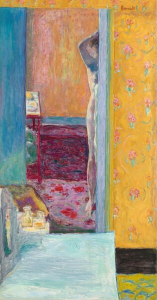 What initially appears to be layered rectangles in marigold orange, butter yellow, rose pink, mauve, peach, aquamarine-blue, turquoise, and deep fuchsia comes into focus as one room seen in a reflection of a tall, rectangular mirror in front of us and to our left in this vertical painting. The left edge of a nude, pale-skinned woman holding at least one hand to her hair is reflected along the right edge of the mirror, which takes up the left two-thirds of the composition. Visible as a vertical strip to our right and a narrow strip along the top edge, the wall behind the mirror is papered with pale pink flowers with mint-green leaves against a field of golden yellow. A pale turquoise rectangle extends into the room from the lower left corner, and some perfume bottles sit beyond the far end. The floor of the room in the reflection is patterned with rounded, floral fuchsia shapes against a lilac purple background. A deep magenta field below an electric blue band suggests paneling beneath a chair rail. The wall above is streaked with peach, pink, and yellow. A frame-like table to our left at the back of the room perhaps holds embroidery. The woman’s body is painted in tones of soft pink with cool blue shadows. She holds the arm and hand we can see up to her chestnut brown hair. Only the side of the head and ear, shoulder, arm, breast, hip, and her right leg are captured in the mirror. The scene is painted with loose, visible brushstrokes so some of the detail is difficult to make out, and it takes time to puzzle out what the scene captures. The artist signed the work with red paint in the upper right corner: “Bonnard.”