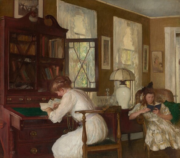 A young woman writes at a desk and a teenage girl reads a book in an armchair in an opulent room in this nearly square painting. Both women have rosy, peach-colored skin and honey-brown hair. To our left, the woman is shown from the knees up as she sits at a tall, mahogany-red, secretary desk. The desk has an emerald-green, tilted writing surface and two shelves packed with books and covered by glass doors, one of which is open. The desk has brass pulls on the drawers under and behind the writing surface, and the cabinet is topped with two curling scrolls to create a triangular pediment. The woman bends over her paper, facing our left in profile as she leans over and looks down at her writing. Her hair is loosely rolled up and pinned in place. She wears a white dress with ruffled, elbow-length sleeves and a lilac-purple sash. Golden chains hang from her neck almost to her lap, and a gold bracelet encircles her wrist. To our right and near the back corner of the room, the girl sits in a high-backed, wicker armchair. She hooks her right elbow, to our left, over the arm of the chair and leans in that direction, with a green pillow tucked into to her other side. Her body faces us and she looks down at a blue book in her hands. She has a round face, a straight nose, and her lips are closed. The girl’s hair is half pulled up in a dark bow atop her head as the rest falls around her shoulders. Her dress is streaked with pale gray, white, and harvest yellow, and is tied at the waist. Between the women, a dark brown cabinet or table holds a glass decanter with a glass stopper and lamp with a shiny, bulbus, white base and an off-white, rounded shade. Warm sunlight pours in from the two tall windows framed with ruffled, silvery-white curtains that flank the table, between the women. Mottled moss green and butter yellow suggest trees outside. The jamb of a French door runs along the right edge of the painting, beyond the reading girl. Several framed pictures hang on the sage-green walls. The artist signed the painting in the lower right: “Tarbell.”